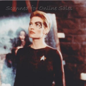 May include: A long-sleeved black jumpsuit featuring a metallic Starfleet insignia on the chest. The garment includes a dark, textured ocular implant over the left eye and a metallic mechanical hand covering, with the text Scanned for Online Sales.