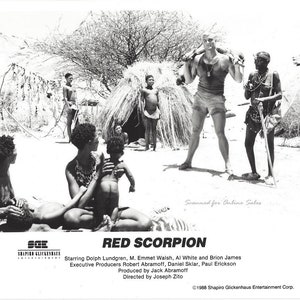May include: Black and white movie poster for the film "Red Scorpion" starring Dolph Lundgren. The poster features a scene from the film with Dolph Lundgren standing in front of a hut with several people in the background.