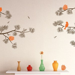 May include: A wall decal featuring a stylized pine branch with orange birds and pine cones. The decal is shown on a light beige wall with four vases on a white shelf below.