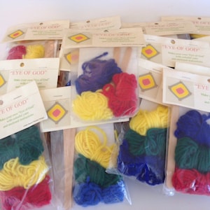 May include: Multiple packages containing craft supplies for making an "Eye of God" craft. Each package includes yarn in red, yellow, blue, and green colors, along with a wooden dowel and instructions.