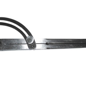 May include: A silver compass with a black adjustment knob. The compass has a pointed tip and a circular base.