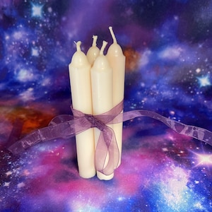 Peut inclure: Un lot de quatre bougies effil&eacute;es blanc cass&eacute; attach&eacute;es ensemble par un ruban violet transparent. Chaque bougie pr&eacute;sente un sommet arrondi et une m&egrave;che en coton. Les bougies sont dispos&eacute;es verticalement en groupe, maintenues par le ruban.