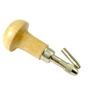 May include: A wooden handled metal tool with a metal drill bit and a metal rod. The tool is used for drilling holes in jewellery.
