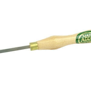 Peut inclure: Un outil de sculpture à manche en bois avec un embout en laiton et une lame en acier. Le manche est marqué "S.J.& J.B. ADDIS" dans un cercle doré sur fond vert.