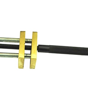 May include: A brass and black metal tool with a handle and two adjustable clamps. The tool is used for holding and securing objects.