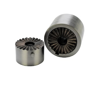 May include: Two cylindrical metal objects with a radial design on the top and a textured interior. One object is upright, and the other is on its side. The objects are made of a brushed metal material.