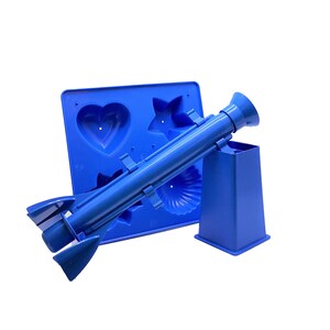 Può includere: Stampo in plastica blu con forma di cuore, stella e conchiglia. Uno strumento in plastica blu con un beccuccio è attaccato allo stampo.