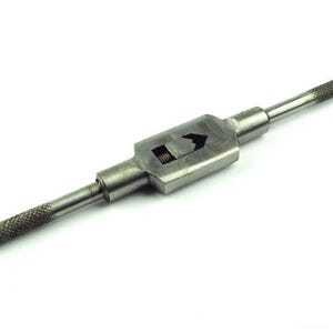 May include: A metal tap wrench tool with a central body and two textured handles. The tool is designed for holding and turning taps, with a hole at the end of one handle. The tool is made of steel.