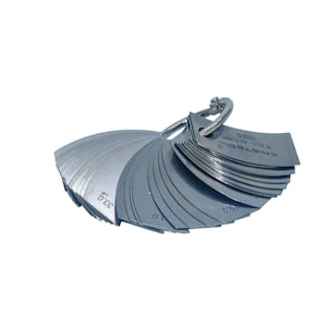 May include: A silver metal feeler gauge set with a ring handle. The gauge has a range of 0.005 to 0.500 inches. The gauge is used to measure the thickness of materials.