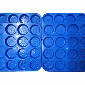 May include: Four blue silicone baking moulds with various holiday and seasonal designs. The moulds are arranged in two rows of two. Each mould has 12 round cavities with different designs, including a Christmas tree, a pumpkin, a heart, and a flower.