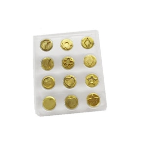 May include: A clear plastic sheet with 12 gold-colored metal stamp heads in a grid pattern. The stamp heads have different designs, including a heart, star, flower, and diamond.