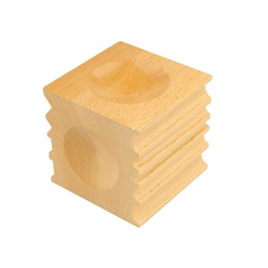 May include: A light-colored wooden cube with a carved, rounded indentation on two sides and a ridged design on the edges. The cube is made of a light-colored wood and is set against a white background.