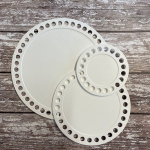 May include: Three white plastic circular loom boards of different sizes. The boards have holes around the edges for crocheting.