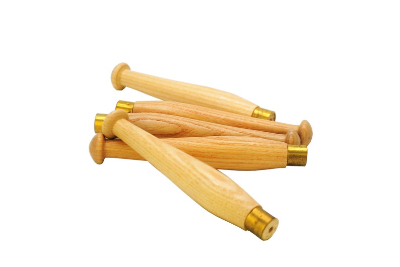 May include: A group of five wooden bobbins with brass tips. The bobbins are arranged in a pile, with the tips of the bobbins facing the camera.