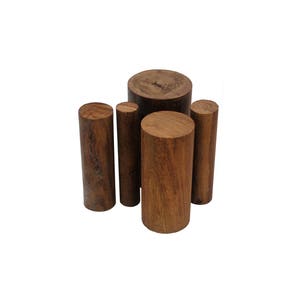May include: Four wooden dowels of varying sizes, all with a rich brown color and a natural wood grain pattern. The dowels are arranged in a staggered formation, with the largest dowel at the top and the smallest dowel at the bottom.