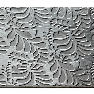 May include: A silver metal sheet with a repeating pattern of embossed stylized leaves. The leaves are arranged in a random pattern and have a slightly textured surface.