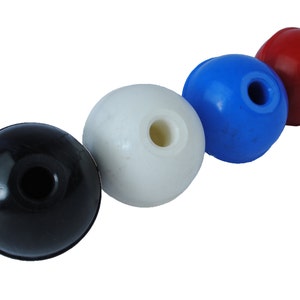 May include: Four round plastic balls with a hole in the center. The balls are black, white, blue, and red.