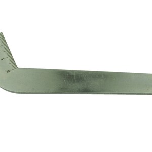 Peut inclure: Un outil en métal argenté avec une poignée incurvée et une échelle graduée marquée de 0 à 2. L'outil est utilisé pour mesurer les angles.