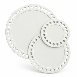 May include: Three circular white discs of varying sizes, each featuring a smooth, solid centre and a wide outer border perforated with a series of evenly spaced, small circular holes arranged in a ring around the perimeter of the object.