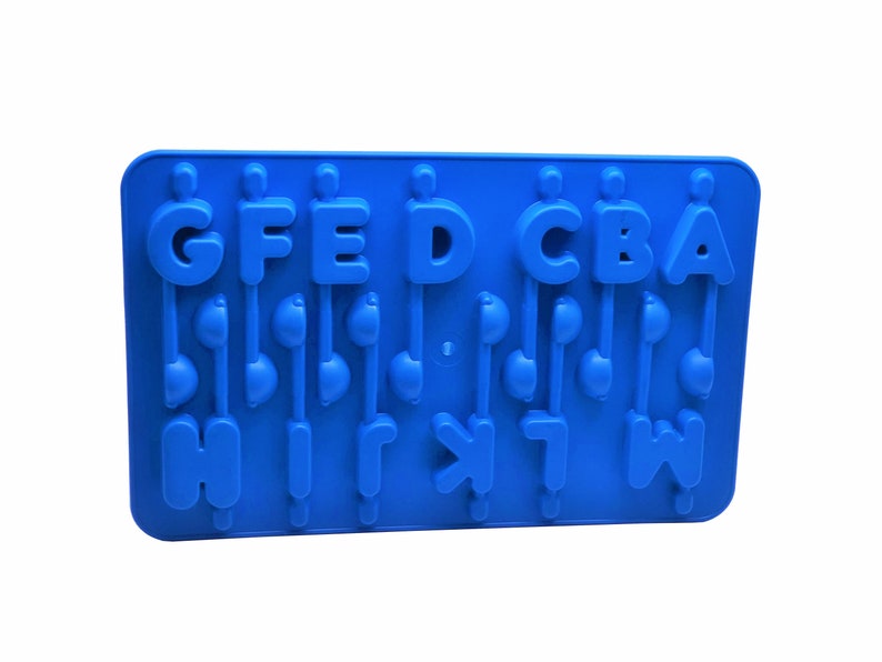 K&ouml;nnte beinhalten: Eine leuchtend blaue Silikonform mit den Buchstaben A bis W. Die Buchstaben sind mit Designs in Form von Noten verbunden. Die Form ist f&uuml;r die Herstellung von Eisw&uuml;rfeln, Pralinen oder anderen Leckereien konzipiert.