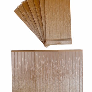 Könnte beinhalten: Ein Satz von acht braunen Wandverkleidungsplatten in Holzoptik. Die Platten haben ein vertikales Holzmaserungsmuster und eine leicht erhöhte Kante. Die Platten sind fächerförmig angeordnet, wobei die obere Platte die größte und die untere Platte die kleinste ist.