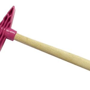 May include: A pink plastic mallet with a wooden handle. The mallet has a flat, rectangular head with a textured surface.