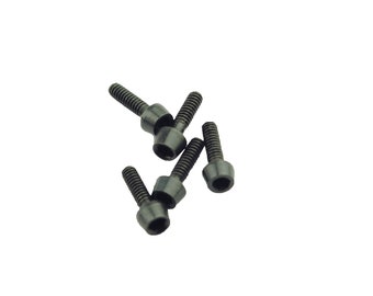 May include: A collection of dark gray socket head cap screws, also known as Allen bolts, scattered against a white background. Each screw has a threaded shaft and a hexagonal socket head.