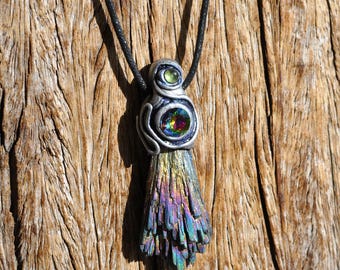 May include: A pendant featuring a raw, iridescent kyanite crystal cluster at the base, topped with a silver-toned sculpted setting. The setting holds a central circular, multi-colored faceted stone and a smaller, round, light green stone above it.