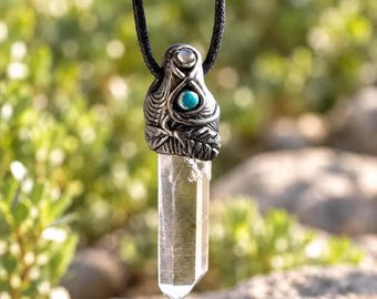 May include: A pendant necklace featuring a clear, hexagonal quartz crystal point suspended from a black cord. The silver-toned metal cap is textured with leaf-like engravings and set with a small, round, bright turquoise stone.