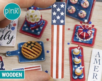 May include: A set of miniature wooden decorations for a 4th of July celebration. The decorations include a pie, cupcakes, a cake, and a sign that says "America".