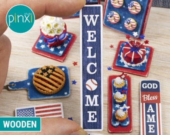 May include: Miniature patriotic-themed food and decor items. Includes a wooden sign that says "WELCOME" with a baseball, miniature cupcakes, a pie with an American flag design, and other decorative elements in red, white, and blue.
