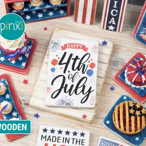 May include: Wooden sign with the text "Happy 4th of July" in red, white, and blue. The sign is surrounded by miniature cakes and pies decorated with red, white, and blue.