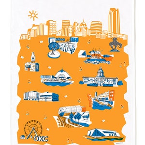 May include: A white tea towel with a yellow outline of Oklahoma City, featuring landmarks like the state capitol building, the Oklahoma City Museum of Art, and the Myriad Botanical Gardens. The text "OKLAHOMA CITY" is printed in gray at the bottom.