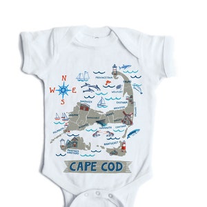 May include: White baby onesie with a map of Cape Cod printed on the front. The map shows the towns and cities on the Cape, including Provincetown, Truro, Wellfleet, Eastham, Brewster, Chatham, Falmouth, Mashpee, Barnstable, Dennis, Yarmouth, Bourne, and Martha's Vineyard. The map also includes a compass rose, a lighthouse, a sailboat, a whale, and a bicycle.