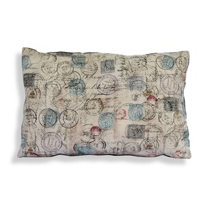 Könnte beinhalten: Ein beigefarbenes Kissen mit einem Vintage-Design mit einem Muster aus verblassten Briefmarken und handschriftlichem Text.