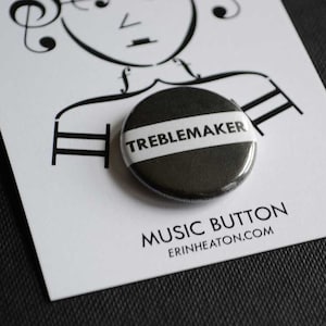 May include: A black and white button with the text "TREBLEMAKER" in white lettering on a black background. The button is on a white card with the text "MUSIC BUTTON" and "ERINHEATON.COM" in black lettering.
