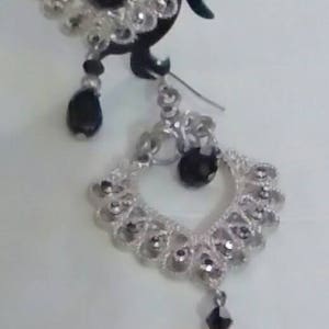 May include: Silver dangle earrings with black beads. The earrings feature a delicate, intricate design.