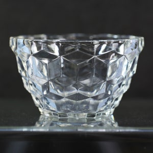 Puede incluir: Un cuenco de vidrio transparente con un patrón geométrico. El cuenco está hecho de vidrio grueso y tiene una forma ancha y redonda.