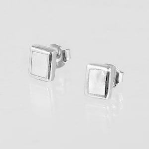 May include: A pair of silver square stud earrings with white mother of pearl insets.
