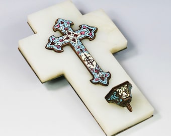 May include: A white marble cross with a decorative, enamel-painted cross on top. The cross is decorated with blue, pink, and white enamel. There is a small, decorative, enamel-painted candle holder on the bottom of the cross.