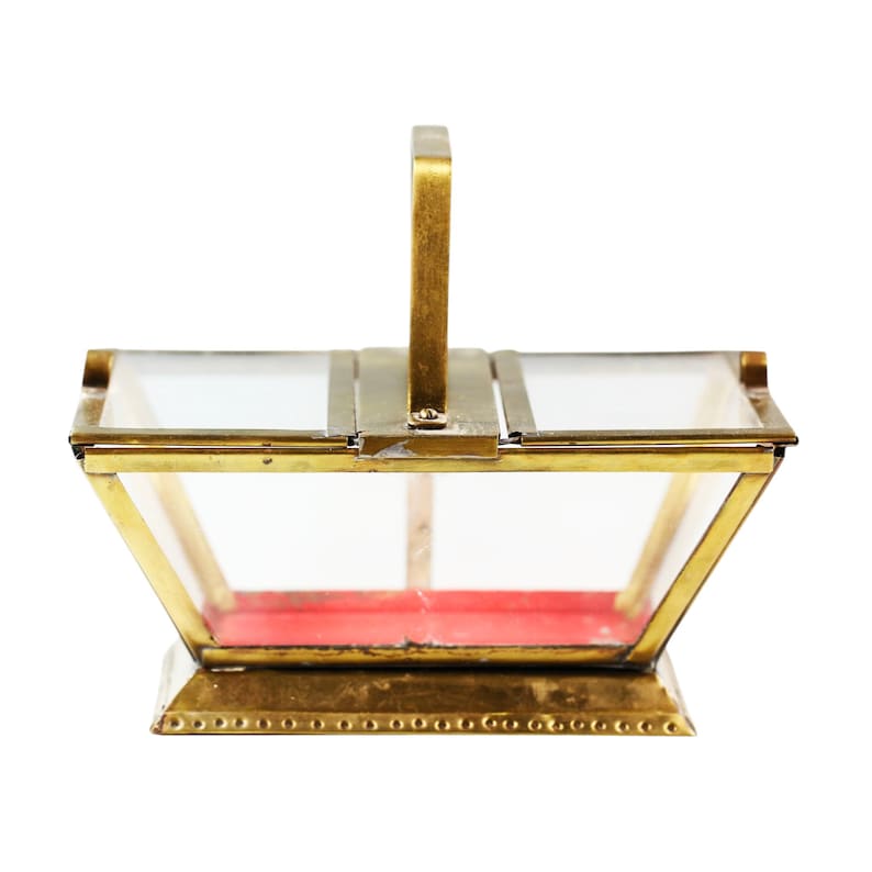 May include: A vintage-style, rectangular glass and brass box with a handle. The box has a red velvet interior and is constructed with clear glass panels and a gold-colored metal frame. The handle is also gold-colored.