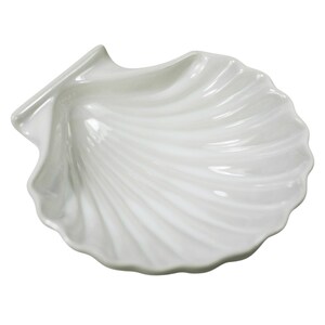 以下が含まれることがあります： 白い貝殻型の装飾皿。光沢のある仕上がりで、貝殻の自然な質感を模倣した、詳細なリブ加工された表面を持っています。エッジはスカラップ状で、リアルなデザインになっています。