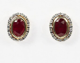 May include: A pair of oval-shaped ruby earrings with a diamond halo setting. The earrings are set in yellow gold.