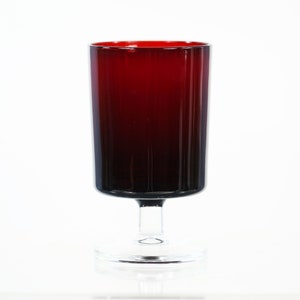 May include: A tall, stemmed glass with a deep red to black gradient. The glass has a cylindrical bowl and a clear, circular base. The stem is also clear, connecting the base to the bowl. The glass is likely made of glass.