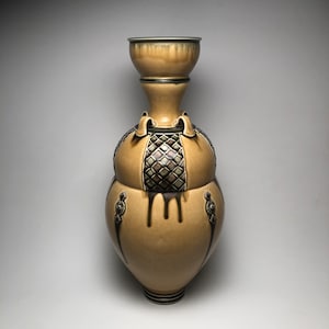 May include: A tall, ceramic vase with a wide, round base and a narrow neck. The vase is decorated with a geometric pattern in shades of brown and black.