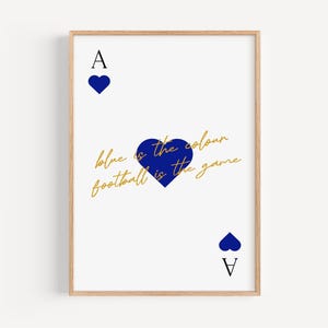 May include: A framed art print featuring a white background with a playing card design. The Ace of Hearts is depicted with blue hearts and the text "blue is the colour football is the game" in gold script. The frame is a light wood color.