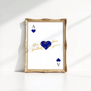 May include: A framed print featuring a playing card design with a gold ornate frame. The card shows a blue heart and the letter "A" at the top and bottom. The text "blue is the colour football is the game" is written in gold.
