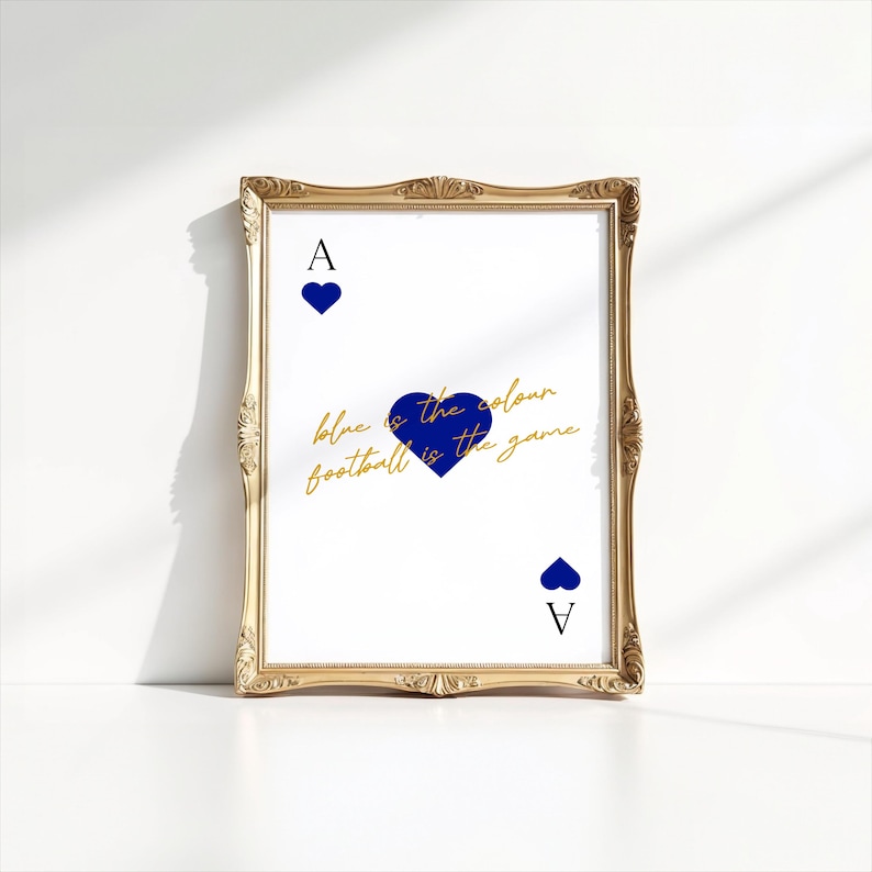 May include: A framed print featuring a playing card design with a gold ornate frame. The card shows a blue heart and the letter "A" at the top and bottom. The text "blue is the colour football is the game" is written in gold.