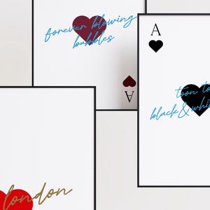 May include: White framed art prints featuring playing card designs. The Ace of Hearts, Ace of Spades, and Ace of Diamonds are displayed. Each card has a heart symbol and text in various colors, including red, black, and blue.