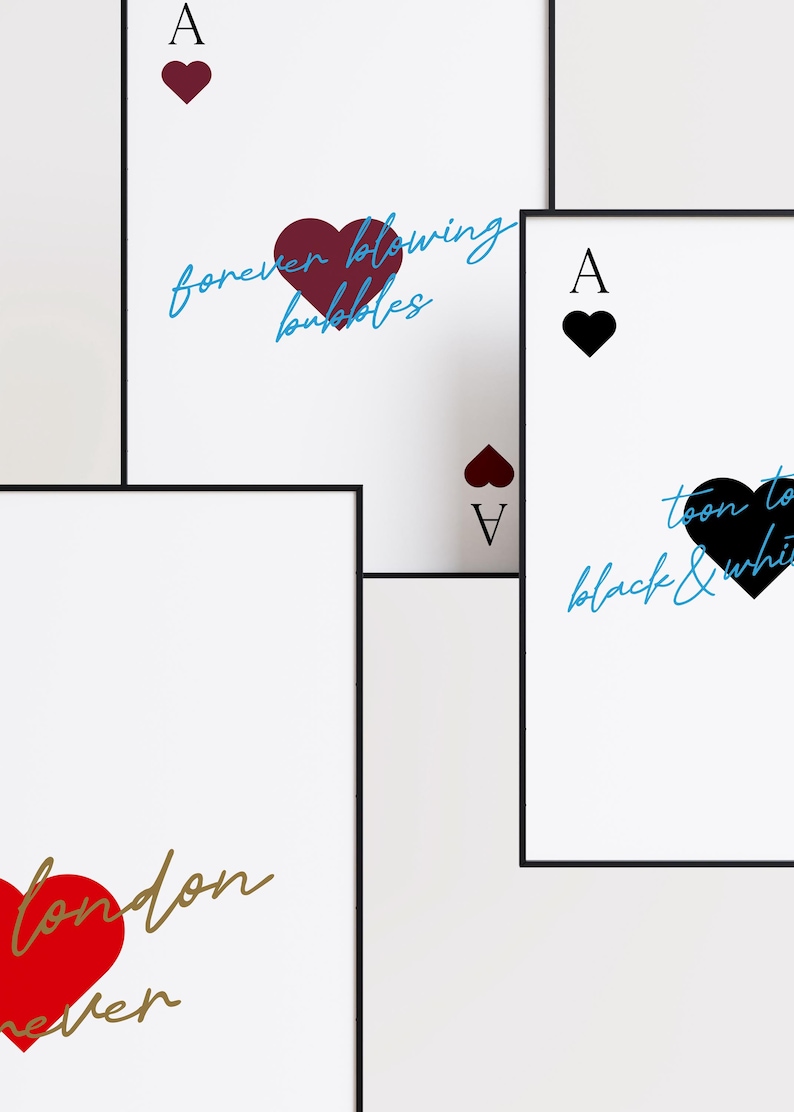 May include: White framed art prints featuring playing card designs. The Ace of Hearts, Ace of Spades, and Ace of Diamonds are displayed. Each card has a heart symbol and text in various colors, including red, black, and blue.